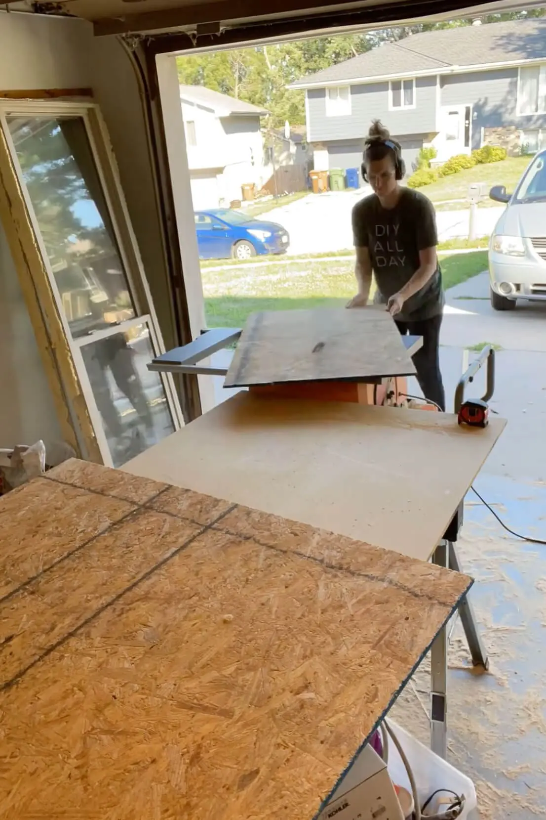 Sliding OSB panels through a table saw to prepare wall sheeting for the DIY fireplace.